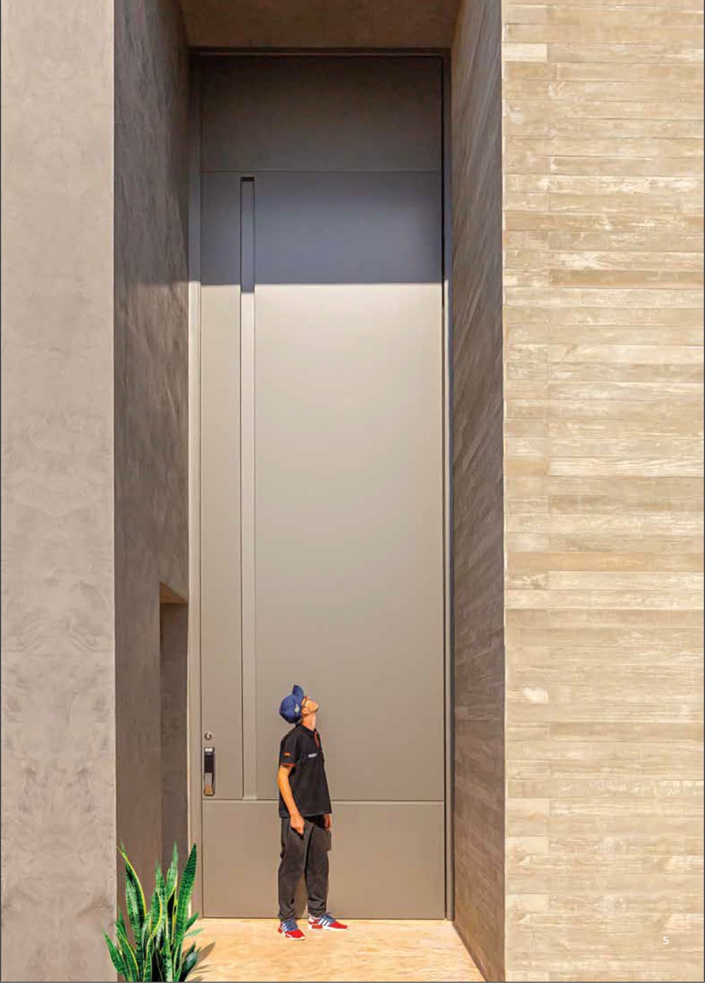 System 115 oversized pivot entry door in a travertine facade — installed project